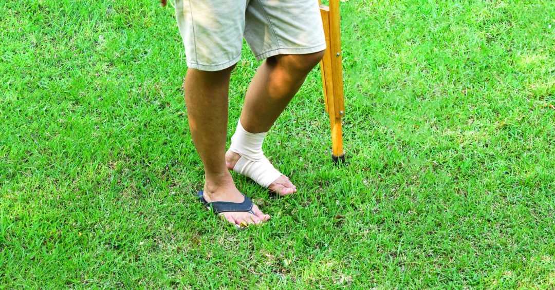 The picture shows patients with ankle injuries with bandages ankle brace and use crutches to support walking on the lawn. Healthcare and medical concept.